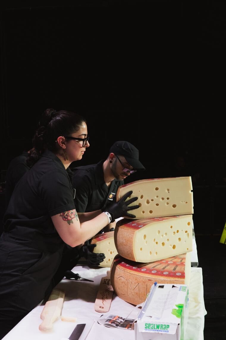 Emilia in black gloves stacking wedges of Emmentaler
